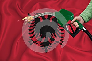 ALBANIA flag Close-up shot on waving background texture with Fuel pump nozzle in hand. The concept of design solutions. 3d