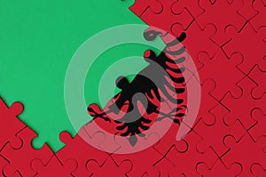 Albania flag is depicted on a completed jigsaw puzzle with free green copy space on the left side