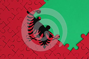 Albania flag is depicted on a completed jigsaw puzzle with free green copy space on the right side