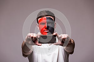 Albanian football fan take selfie photo with phone on grey background.