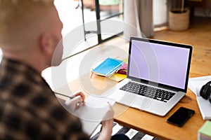 Albino african american man working from home using laptop with copy space photo