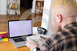 Albino african american man working from home using laptop with copy space photo