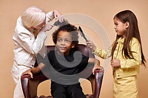 Albino child girl combing curly hair of africanamerican boy isolated