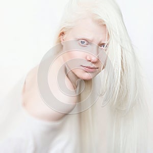 Albino female with white pure skin and white hair. Photo face on a light background. Portrait of the head. Blonde girl