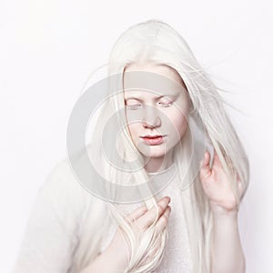 Albino female with white skin and white long hair. Photo face on a light background. Portrait of the head. Blonde girl