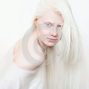 Albino female with white pure skin and white hair. Photo face on a light background. Portrait of the head. Blonde girl photo