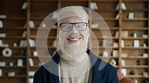 Albino man with happy face standing in library. Businessman smiling at camera