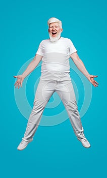 Albino man jumping up on blue background