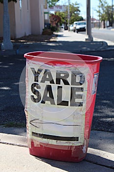 Albuquerque, New Mexico, USA, September 16, 2023, Red trash can with Yard Sale Sign Taped On, on corner sidewalk, Fourth Street