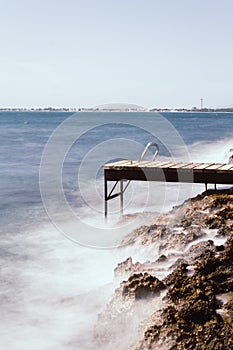 Alcanada beach with wooden ports overlooking the port of Alcudia. Sea enraged against the wooden port