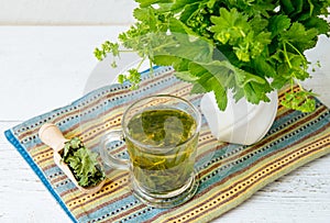 Alchemilla vulgaris, common lady\'s mantle medicinal herbal tea in clear cup. Fresh lady\'s mantle plants in vase.