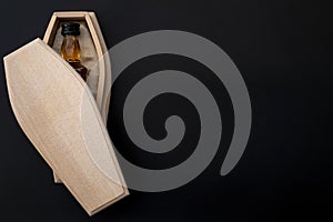 Alcohol abuse kills, despair deaths and drinking problem concept with liquor bottle in wood coffin isolated on dark ominous