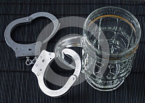 Alcohol addiction. Handcuffs and a glass for beer. Symbolic image of alcoholism.