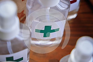 Alcohol antiseptics with the green cross logo on wooden table.