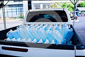 Alcohol for cleaning and sanitizing is contained in gallons on pick-up truck. Many gallon alcohol gel for sanitizing Coronavirus