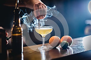 Alcohol cocktail on the bar counter with smoke and cinamon stick