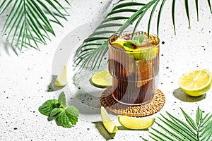 Alcohol cocktail cuba libre with rum, cola, mint and lime in the glass a light background, cookbook recipe top view