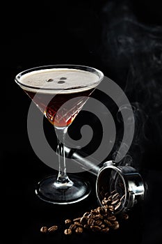 Espresso Martini cocktails garnished with coffee beans, beans in espresso holder in smoke and on black background