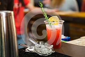 Alcohol cocktail glass on bar counter. Fresh coctail on a color background in plastic glass with pro bar stuff. Drinking cocktails