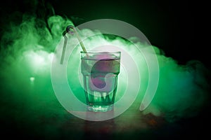 Alcohol cocktail in glass with ice in smoke on dark background. Club drinks concept. One glass of cocktail. Selective focus