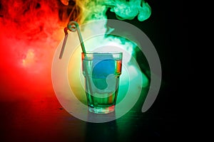 Alcohol cocktail in glass with ice in smoke on dark background. Club drinks concept. One glass of cocktail. Selective focus