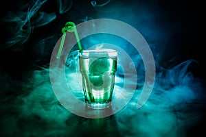 Alcohol cocktail in glass with ice in smoke on dark background. Club drinks concept. One glass of cocktail. Selective focus