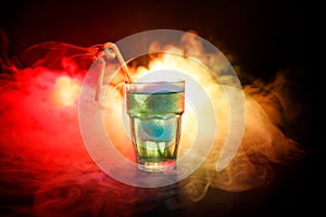 Alcohol cocktail in glass with ice in smoke on dark background. Club drinks concept. One glass of cocktail. Selective focus