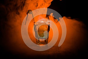 Alcohol cocktail in glass with ice in smoke on dark background. Club drinks concept. One glass of cocktail. Selective focus