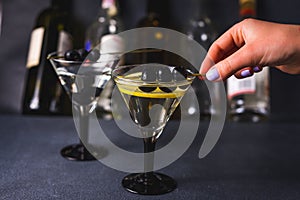 Alcohol cocktail with splash.Dry martini with black olives.Vermouth cocktail inside martini glass over dark background.Martini gla