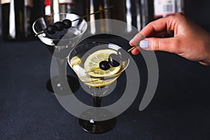 Alcohol cocktail with splash.Dry martini with black olives.Vermouth cocktail inside martini glass over dark background.Martini gla