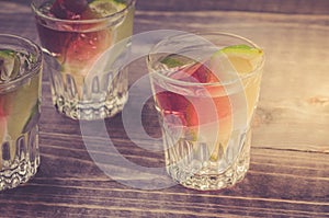 Alcohol shots with a lime/Alcohol shots with a lime on wooden backgrouns. selective focus