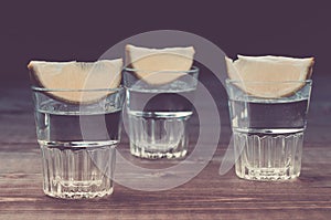 Alcohol shots with a lime on wooden background/Alcohol shots with a lime on wooden background. Toned