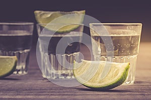 Alcohol shots with a lime on wooden bar counter/Alcohol shots with a lime on wooden bar counter. Toned