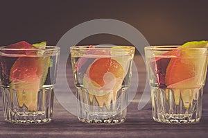 Alcohol shots with a lime on a wooden table/Alcohol shots with a lime on a wooden table. Close up