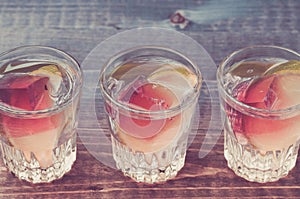 Alcohol shots with a lime on a wooden table/Alcohol shots with a lime on a wooden table. Toned