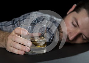 Alcoholic addict man drunk sleeping holding whiskey glass in alcoholism concept