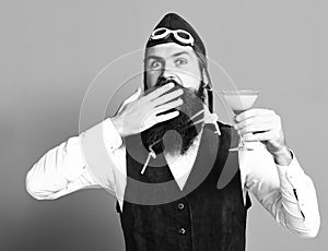 Alcoholic beverage in vintage suede leather waistcoat with hat and glasses on red studio background surprised handsome