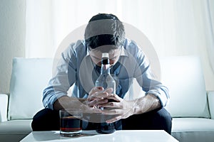 Alcoholic Business man wearing blue loose tie drunk with whiskey bottle on couch