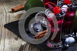 Alcoholic cocktail with blueberry, cinnamon and lime, named berry me, black table, selective focus