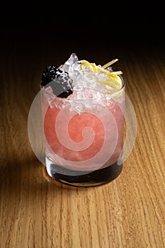 Alcoholic cocktail Bramble based on gin, blackberry liqueur, lemon juice and sugar syrup, decorated with blackberries and lemon ze photo