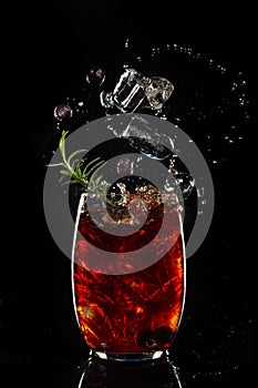 Bramble cocktail with blackberries and crashed ice with splash on black background. Copyspace