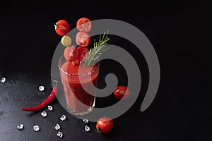 Alcoholic cocktail glass of Bloody Mary with tomatoes and rosemary on a black background, tomato juice