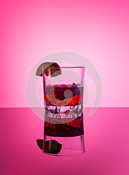 Alcoholic cocktail. Glass with drinks vodka, apple liqueur, ice, apple slice on pink background