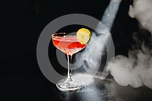 Alcoholic cocktail Greyhound, with vodka, liqueur, grapefruit juice and ice, black background, all in smoke, garnished