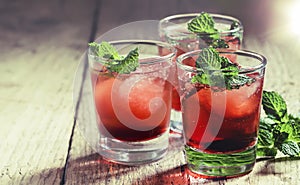 Alcoholic cocktail with white rum, red vermouth, mint and ice cubes, wooden table, selective focus