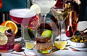 Alcoholic cocktails set, strong drinks and aperitifs, bar tools, bottles on dark green background, hard light. Martini vodka, pink