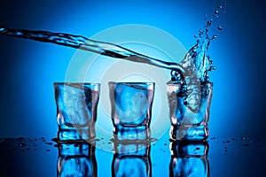 Alcoholic drink in dammed glasses with splashes on a blue background