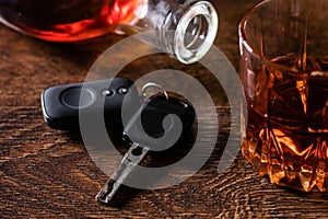 Alcoholic drink in a glass and car keys on a wooden desk. Drunk driving concept
