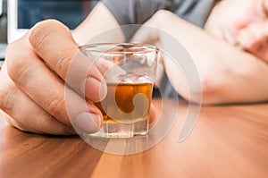 Alcoholic man is sleeping on table. Glass with alcohol in hand