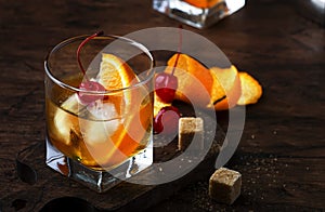 Alcoholic old fashioned cocktail with orange slice, cherry and orange peel garnish